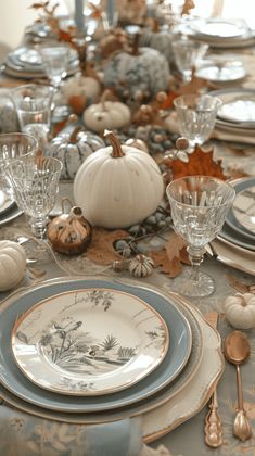 a table set for thanksgiving dinner with pumpkins and gourds