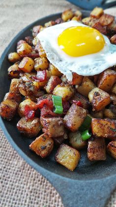 a fried egg on top of potatoes in a frying pan