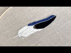 a blue and white feather sitting on top of a piece of fabric