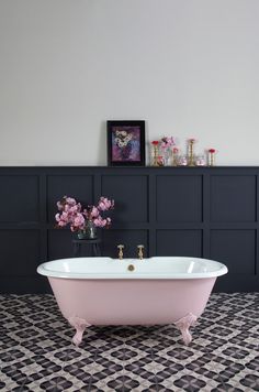 a pink bath tub sitting on top of a black and white tile floor next to a wall