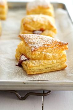 pastries on a baking sheet with powdered sugar and jelly toppings are ready to be eaten