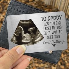 a person holding up a metal card with an image of a baby