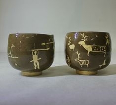 two cups with designs on them sitting next to each other in front of a white background