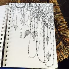 a spiral notebook with an intricate design on the cover and some tassels hanging from it