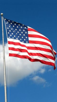 an american flag waving in the wind on a clear day with blue sky and clouds