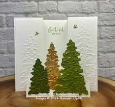 two cards with trees on them are sitting on a wooden table next to a brick wall