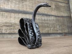 a metal swan figurine sitting on top of a wooden table