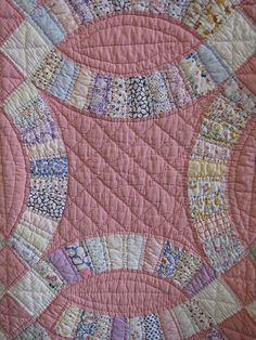 a close up of a quilt on a bed with pink and white designs in the center