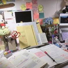 a cluttered desk with many papers and laptops