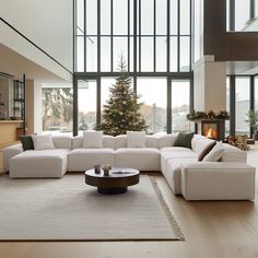 a living room filled with white furniture and a christmas tree in the window sill