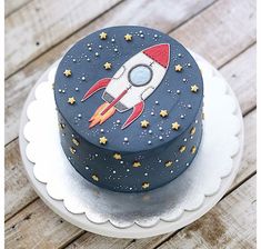 a blue cake with a rocket on it sitting on top of a white platter