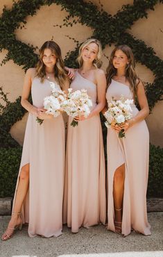 three bridesmaids pose for a photo in front of a wall