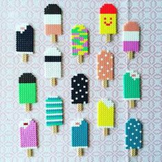 an assortment of popsicles made out of perler beads on a pink background with white lace