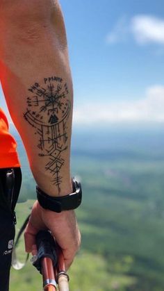 a man with a tattoo on his arm holding onto an umbrella and looking at the sky