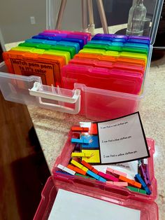 several plastic containers filled with colored pencils on top of a counter next to a notepad