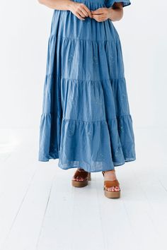 Features Sweetheart neck Flutter sleeves Tiered skirt with floral embroidered detail Smocked back Elastic waist Dusty blue color Pockets Self: 100% Cotton; Lining: 100% Polyester Size + Fit Small 0-4, Medium 4-8, Large 8-12, XL 14-18 Kristin is 5'4", a size 1 and is wearing a Small Runs true to size. Measurements taken while laying flat and then doubled. They do no account for stretch. Click here for shoes Size Bra Band Length Small 34" 49" Medium 36" 49" Large 38" 50" X-Large 40" 50" Bohemian Blue Tiered Skirt Dress, Blue Bohemian Dress With Tiered Skirt, Casual Blue Skirt With Smocked Back, Blue Bohemian Ruffled Dress, Blue Summer Skirt With Smocked Back, Blue Bohemian Dress With Ruffled Skirt, Blue Tiered Skirt For Spring, Blue Skirt With Smocked Back For Summer, Blue Cotton Dress With Ruffled Skirt