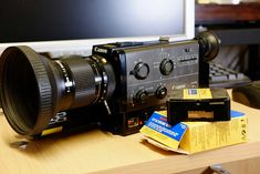 a camera sitting on top of a wooden desk next to a computer monitor and keyboard