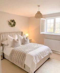 a white bed sitting next to a window in a bedroom