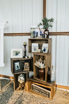 an arrangement of wooden crates with pictures and other items on them in front of a white wall