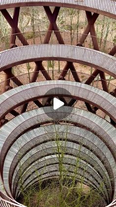 the circular bench is made out of metal and has grass growing in between two sides