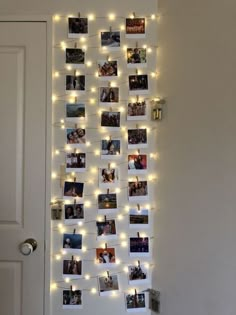 a white door with pictures hanging on it and lights strung from the wall above them