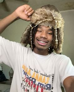 a young man wearing a furry hat with chains around his head and smiling at the camera