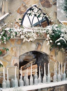 a fireplace with white flowers and candles in front of it