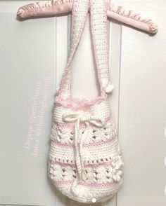 a crocheted purse hanging from a hook on a door handle with a pink ribbon attached to it