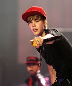 a young boy wearing a red hat and holding a baseball bat in his right hand