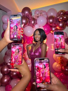 two women holding up their cell phones in front of balloons