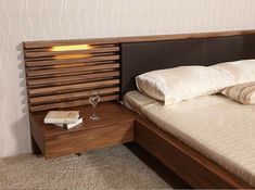 a bed with a wooden headboard and night stand next to a glass of wine