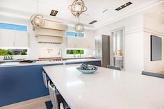 a large kitchen with white counter tops and blue backsplash