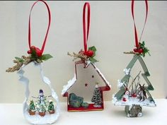 three christmas ornaments are hanging from red ribbon and decorated with snowmen, trees, and houses