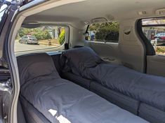 the back seat of a car with two couches and pillows in it's trunk