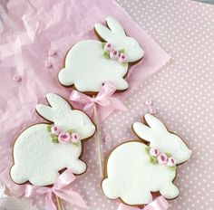 three decorated cookies are sitting on a pink polka dot tablecloth with bows and flowers