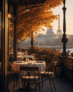 an outdoor dining area with tables and chairs overlooking the river in paris, france at sunset