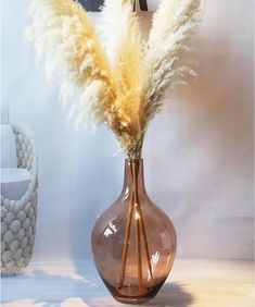 a vase with some flowers in it on a table next to a mirror and chair