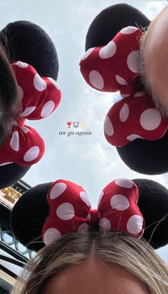 two people wearing minnie mouse ears and one is looking up at the sky with her eyes closed