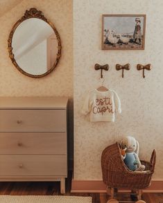 a baby's room with a teddy bear in a pram, dresser and mirror