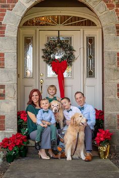 a family sitting on the front steps with their dog and two children in front of them