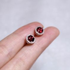 "These stylish earrings have a stunning bright color and the Garnet is surrounded by a halo of shimmering diamonds. Perfect as a gift for yourself, your girlfriend or wife, or your mother. Features * Made to Order. * Metal: 925 Sterling Silver * Custom Color: Silver, Gold, Rose Gold * Main Stone: Garnet, 5mm dia Round Shape, 2pcs * Side Stone: Cubic Zirconia Garnet Ring: * Bypassing: https://etsy.me/3uShIbD Be sure to hit \"favorite\" on the right so it remains in your favorites list and/ or add Birthstone Engagement Rings, Halo Diamond Earrings, Diamonds Earrings, Peach Morganite, Stylish Earring, Ruby Diamond, Jewelry For Her, Red Ruby, Garnet Rings