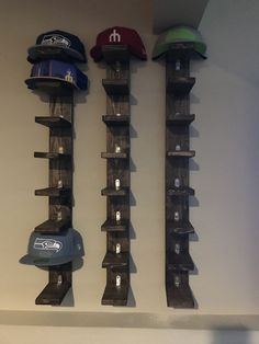 three hats are hanging on the wall next to each other, and there is a hat rack in front of them