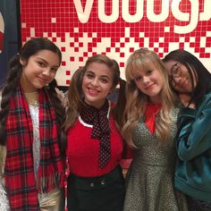 four girls are posing for the camera in front of a vodafox sign