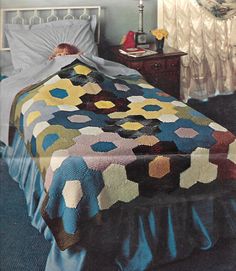 a woman laying in bed with a quilt on it