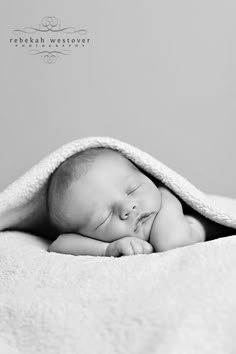 a black and white photo of a baby wrapped in a blanket with his eyes closed