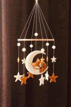 a baby crib mobile with a fox on the moon and stars hanging from it