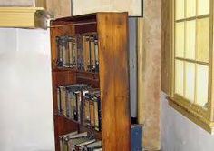 an old wooden bookcase with many books on it in the corner of a room