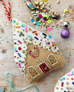 a gingerbread house ornament on a table surrounded by other ornaments and decorations