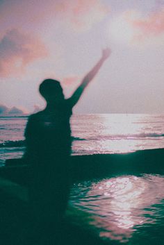 a person standing in the water with their arms up