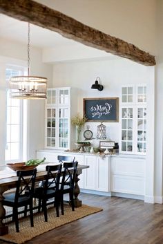 a dining room table and chairs in front of a tv mounted on the wall above it